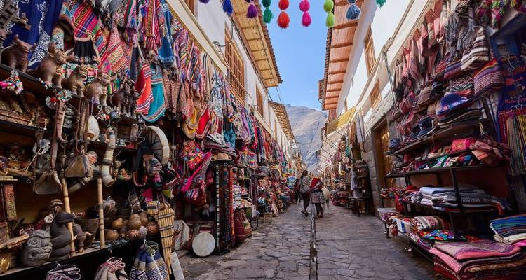 Rue de marché artisanal animée à Ollantaytambo bordée de textiles colorés et d'artisanat andin.
