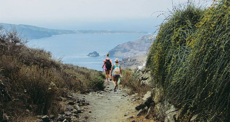 Senderistas caminando por un sendero costero con una vista panorámica del mar.