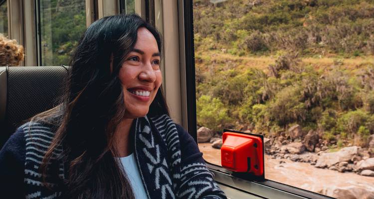 Femme souriante regardant par la fenêtre d'un train un paysage qui défile.