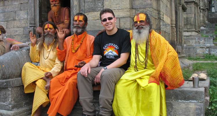 Toerist zit met hindoeïstische sadhoes bij een tempel.