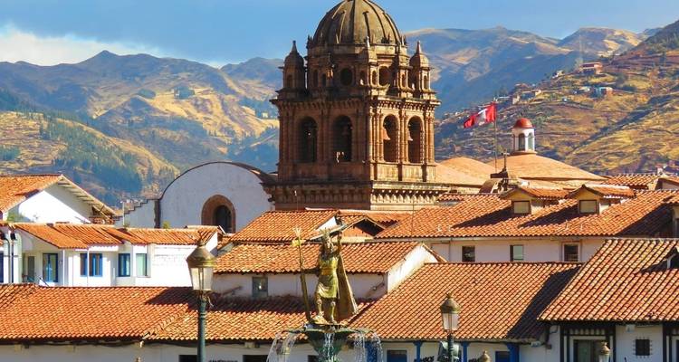 Cathédrale historique et fontaine à Cusco avec montagnes.