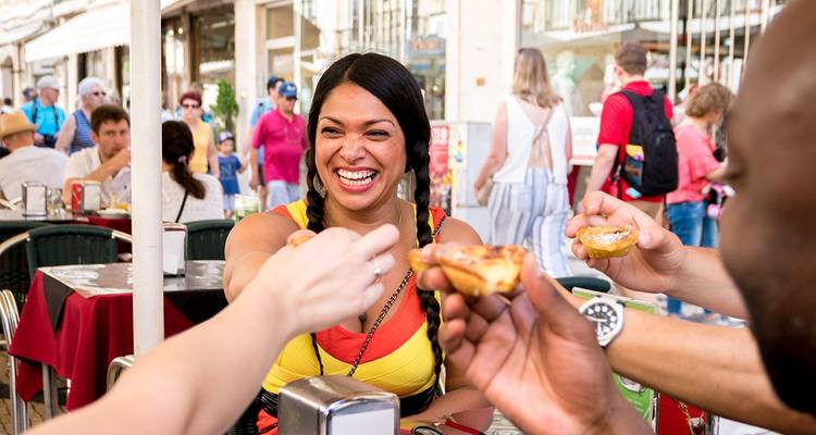 People enjoying Portuguese pastries at an outdoor cafe.