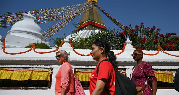 Los viajeros caminan en el sentido de las agujas del reloj alrededor de la estupa de Boudhanath, decorada con coloridas banderas de oración.