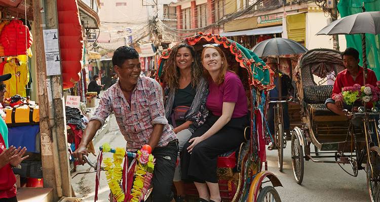 Los turistas se ríen mientras viajan en un colorido rickshaw de ciclo por las concurridas calles de Katmandú.
