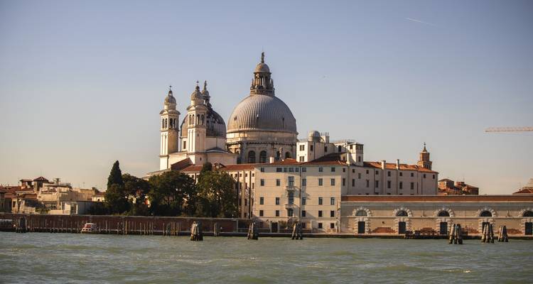 Les dômes de Santa Maria della Salute s'élèvent au-dessus de l'horizon de Venise, vus de l'autre côté du lagon scintillant.