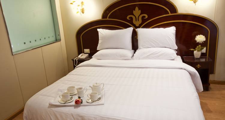 Chambre d'hôtel avec un lit bien rangé et un service à thé.