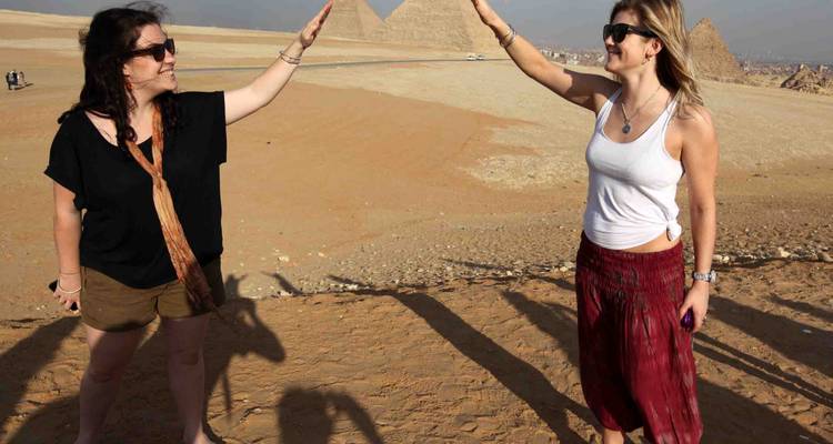 Deux femmes se congratulant avec des pyramides derrière elles.