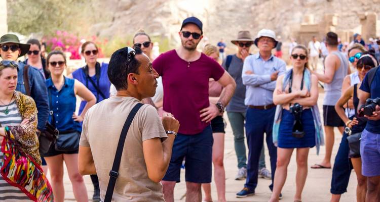 Un guía turístico hablando a un grupo de turistas en un yacimiento antiguo.