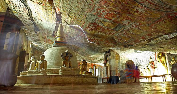 Estatuas de Buda y estupa bajo el techo con frescos vividos dentro del Templo de la Cueva de Dambulla.