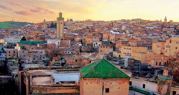 Une vue panoramique d'une ville marocaine avec des minarets et un coucher de soleil.