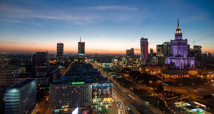 Skyline de Varsovia al atardecer con rascacielos iluminados.