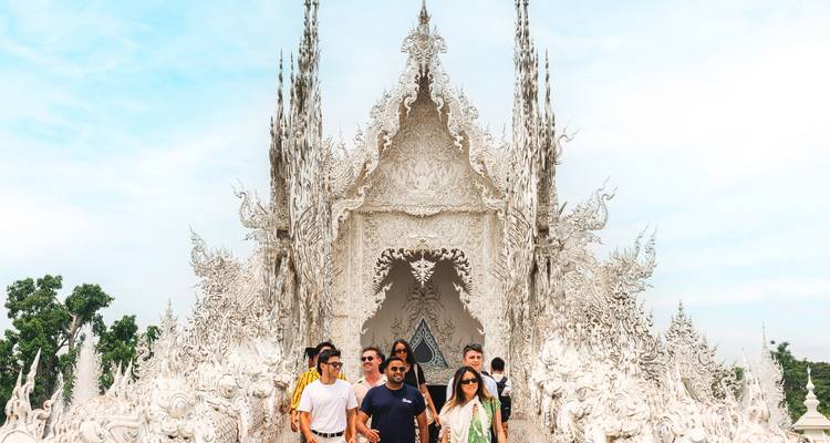 Un grupo de viajeros posa en la ornamentada fachada blanca del famoso Templo Blanco con tallados intrincados.