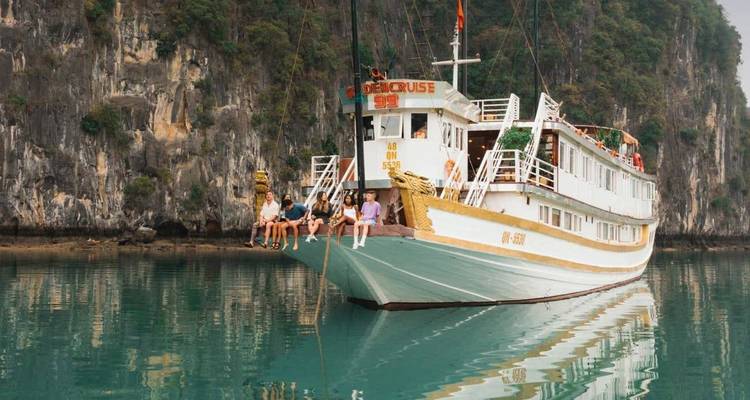 Bateau de croisière en bois classique ancré parmi les falaises calcaires sur les eaux émeraude de la baie d'Halong.