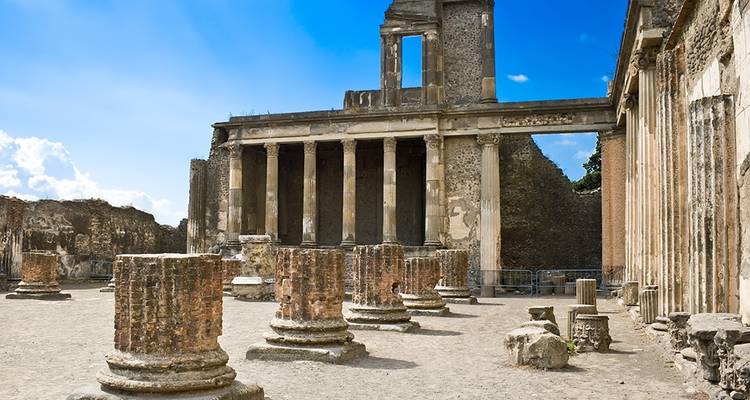 D'anciennes colonnes de pierre et les ruines d'un temple classique se dressent sous un ciel bleu éclatant à Pompéi.
