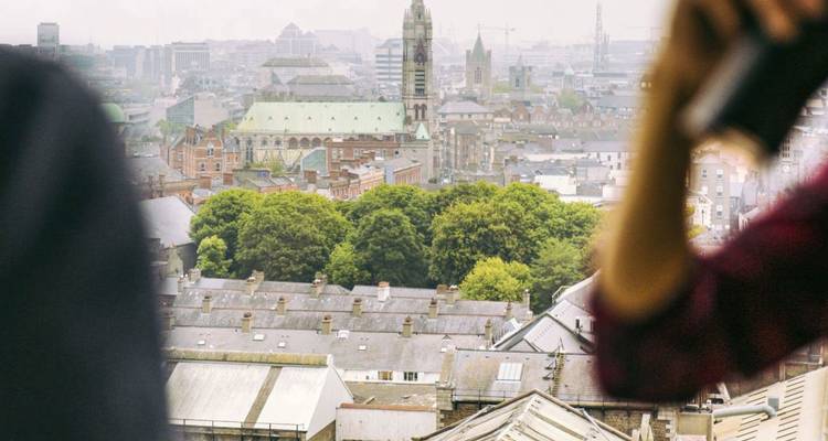 Verschwommene Panoramablick über Dublin mit entferntem Dom, eingerahmt von zwei unscharfen Betrachtern.