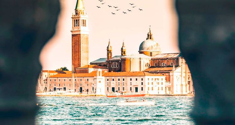 Vue encadrée de l'île de San Giorgio Maggiore et de son clocher à travers une arcade de pierre.