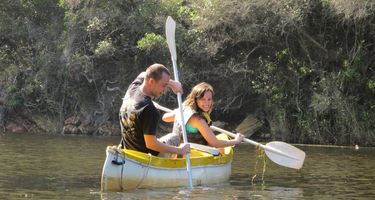 Couple faisant du kayak sur une rivière calme avec une végétation luxuriante.