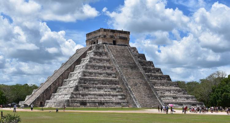 The Chichen Itza pyramid with tourists exploring the area.