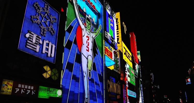 Enseignes au néon illuminées dans une rue japonaise animée la nuit.