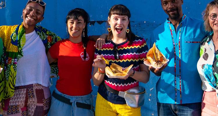 Eine lebhafte Gruppe, die mit Tamales vor einer blauen Wand posiert.