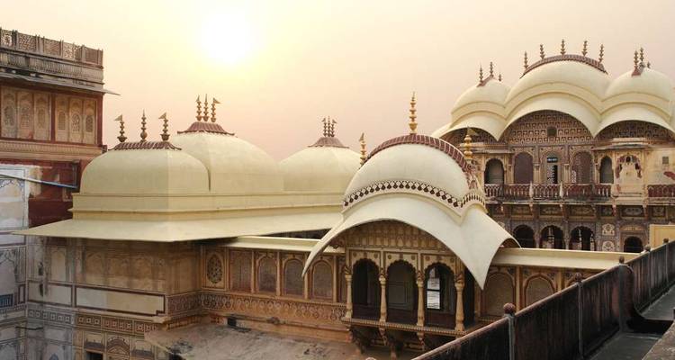 Elegante palacio rajastani con cúpulas color crema y un intrincado trabajo de celosía que brilla suavemente al amanecer.