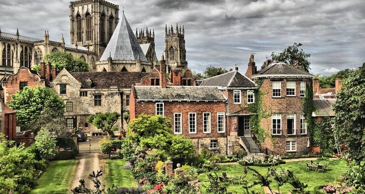 Un jardin luxuriant avec des bâtiments historiques et une église en arrière-plan.