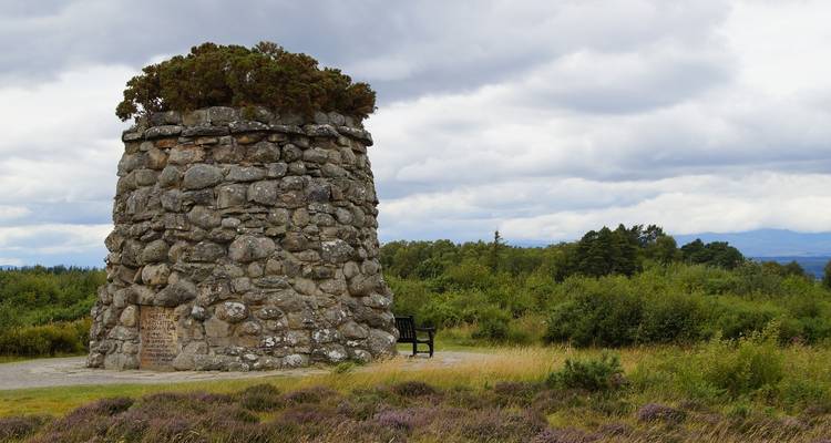 Stone monument set against a cloudy sky in an open field.