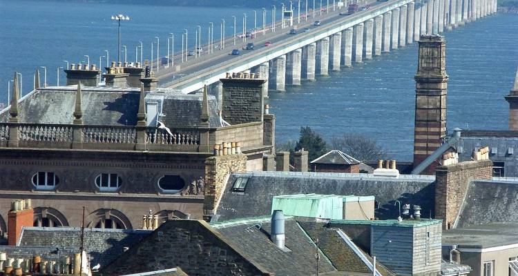 City rooftops with a large bridge spanning across a river in the background.