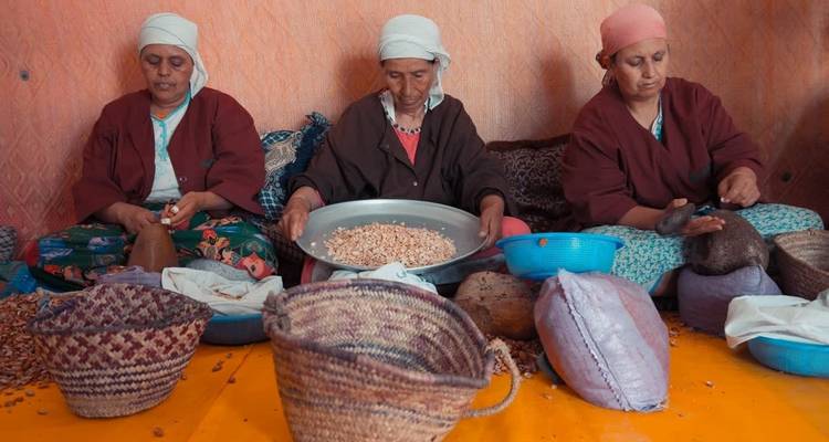 Trois femmes portant des vêtements traditionnels préparent de la nourriture.