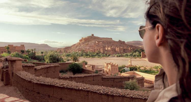 Une personne avec des lunettes de soleil observant Ait Benhaddou, un site du patrimoine mondial de l'UNESCO.