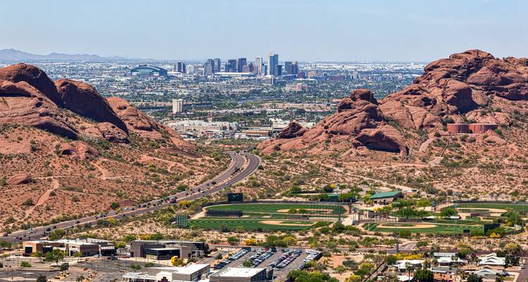 Vue panoramique de la ville de Phoenix au-delà des buttes de grès rouge et des routes sinueuses du désert.