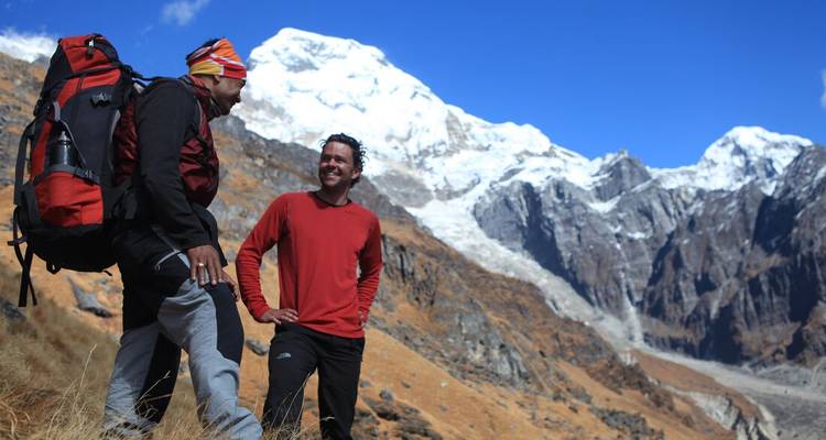 Les trekkeurs font une pause sur un versant alpin avec la chaîne enneigée de l'Annapurna en arrière-plan.