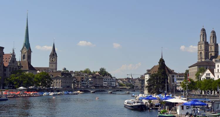 Le front de mer de Zurich avec des bateaux, des ponts et des tours historiques.