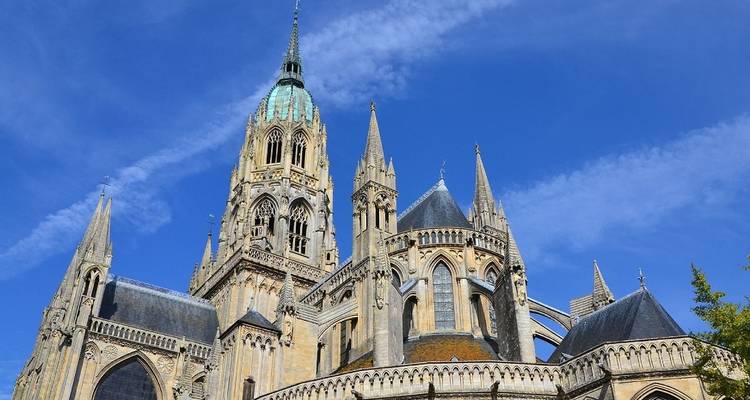 Una catedral con una aguja ornamentada bajo un cielo azul despejado.