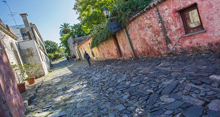 Calle de adoquines con paredes coloniales en tonos pastel en la histórica Colonia del Sacramento