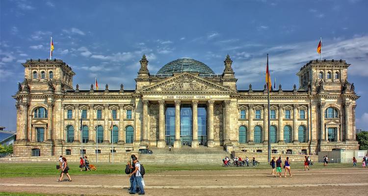 Grand bâtiment historique avec un dôme de verre et des gens qui marchent.