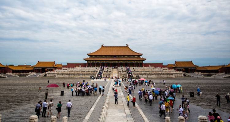 Patio amplio de la Ciudad Prohibida de Beijing lleno de turistas acercándose al gran salón del palacio bajo un cielo nublado