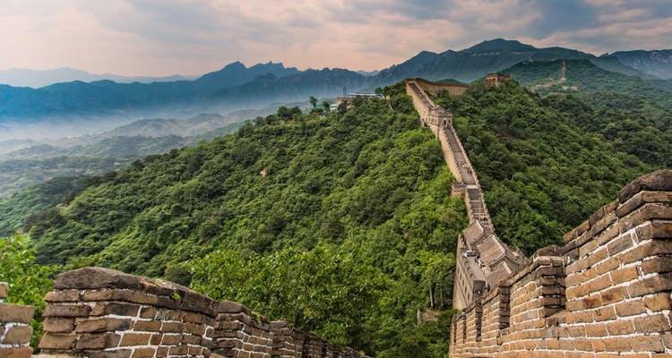 Los icónicos muros de piedra de la Gran Muralla serpentean sobre las exuberantes crestas montañosas verdes hacia la distancia brumosa