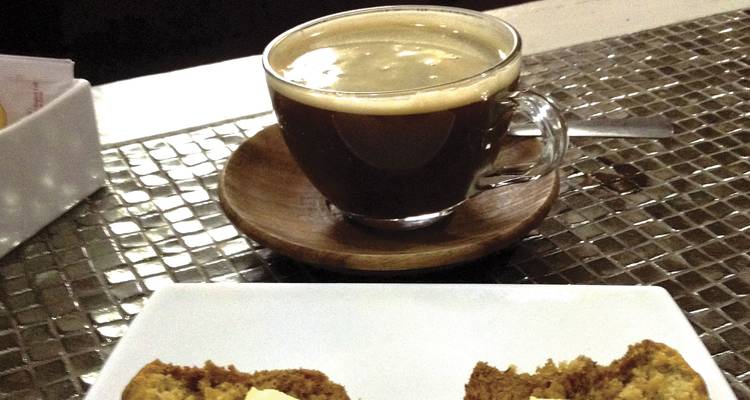 Primer plano de una taza de café y un pastel en una mesa de cafetería