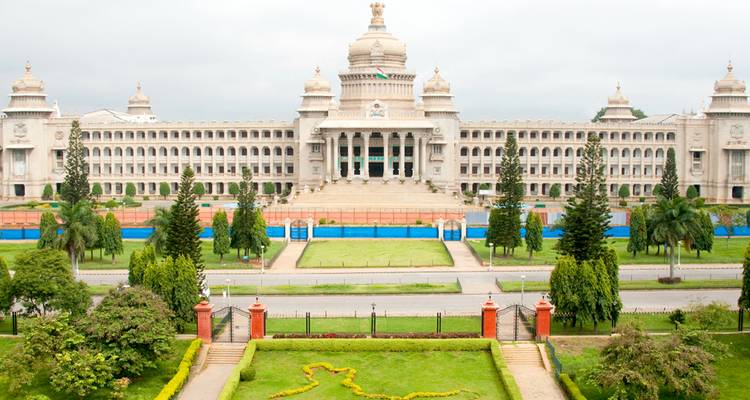 Impresionante edificio gubernamental Vidhana Soudha de color blanco enmarcado por jardines bien cuidados en un día nublado