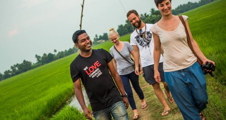 Groep mensen loopt over een smal pad in een groen landschap.
