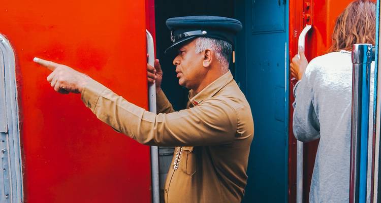 Treincondutor wijzend terwijl hij in de deuropening staat.