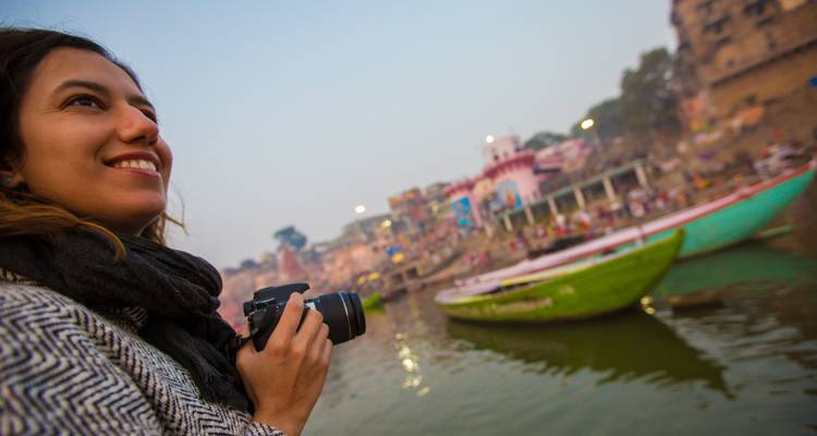 Una mujer con una cámara disfrutando de una vista panorámica del río al atardecer.