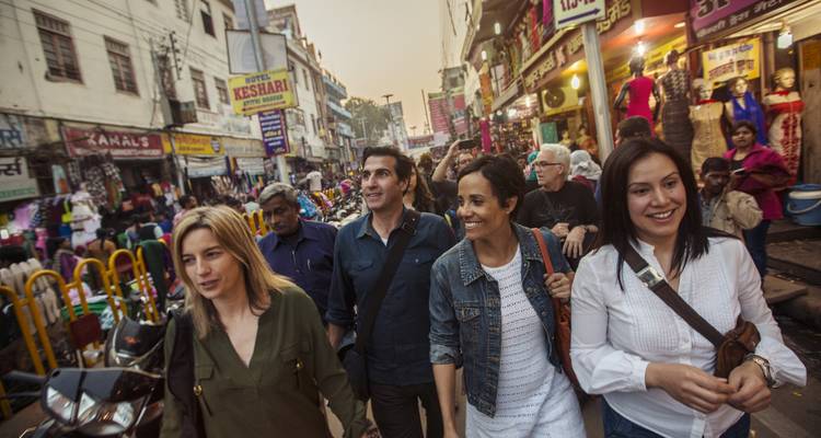 Grupo de personas caminando por un concurrido mercadillo con tiendas a los lados.