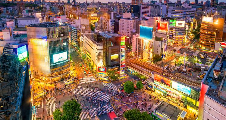 Vue aérienne vibrante du carrefour Shibuya et des gratte-ciel environnants illuminés au crépuscule.