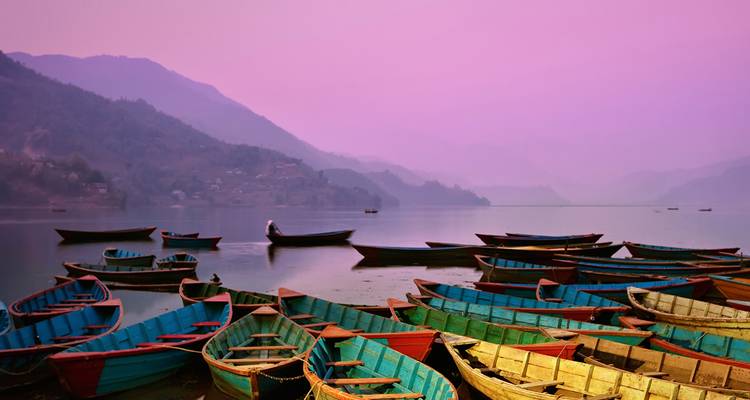 Coloridas barcas de madera reflejadas en las aguas tranquilas del lago bajo un soñador atardecer púrpura