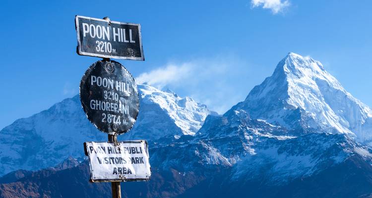 Cartel de metal marcando el punto de vista de Poon Hill con la cordillera del Annapurna cubierta de nieve de fondo