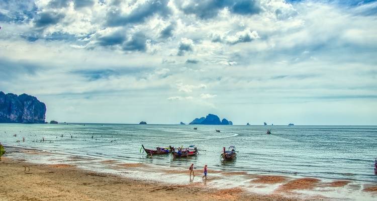 Des gens profitant d'une plage avec des bateaux à longue queue à Krabi.