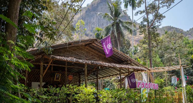 Rustikales Restaurant im Freien mit G Adventures-Flagge vor einer Kalksteinfelsenwand
