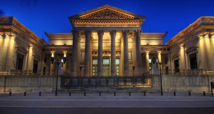 Palais de justice néoclassique illuminé la nuit.